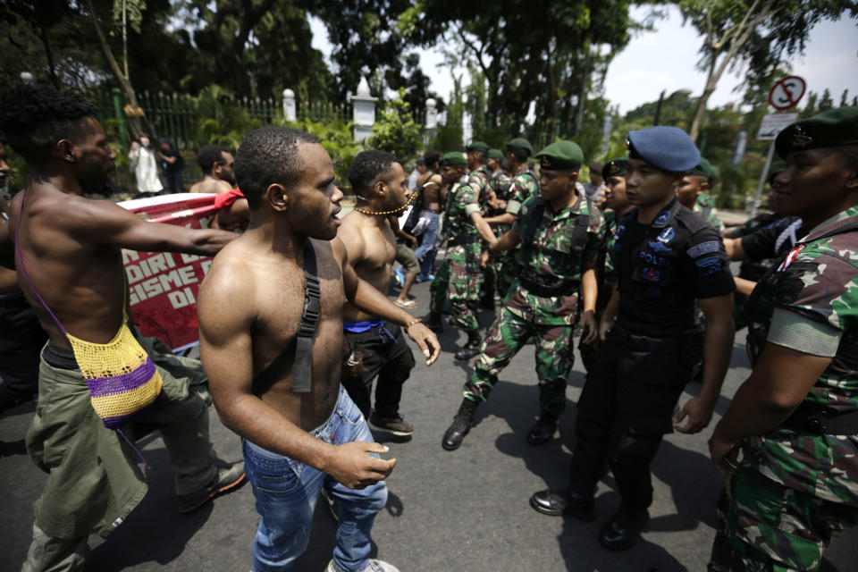 Papuan activists confront police and soldiers during a brief scuffle at a rally near the presidential palace in Jakarta, Indonesia, Thursday, Aug. 22, 2019. A group of West Papuan students in Indonesia's capital staged the protest against racism and called for independence for their region. (AP Photo/Dita Alangkara)