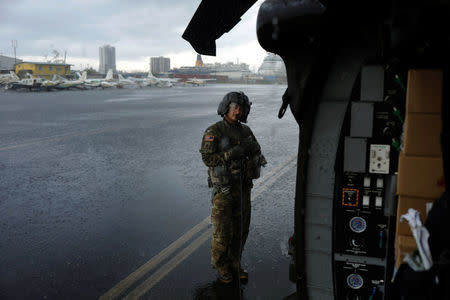 Crew chief Kenney shelters under the blade of an HH-60 Blackhawk helicopter from 101st Airborne Division's "Dustoff" unit preparing to take off during recovery efforts following Hurricane Maria, in Isla Grande, Puerto Rico, October 6, 2017. REUTERS/Lucas Jackson