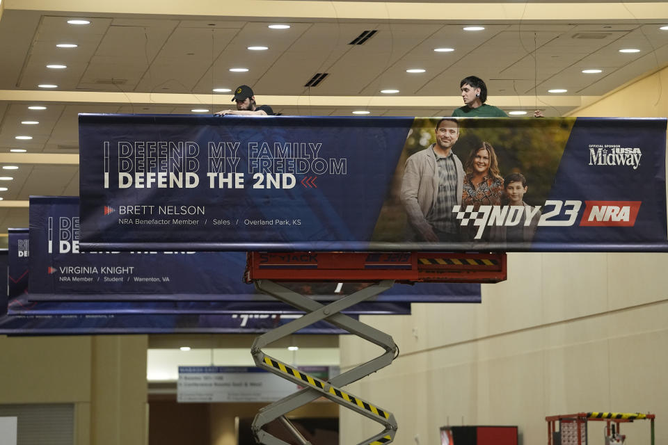 Workers hang a banner in the Indiana Convention Center advertising the NRA Convention, Thursday, April 13, 2023, in Indianapolis. The convention starts Friday, April 14 and end on Sunday, April 16. (AP Photo/Darron Cummings)