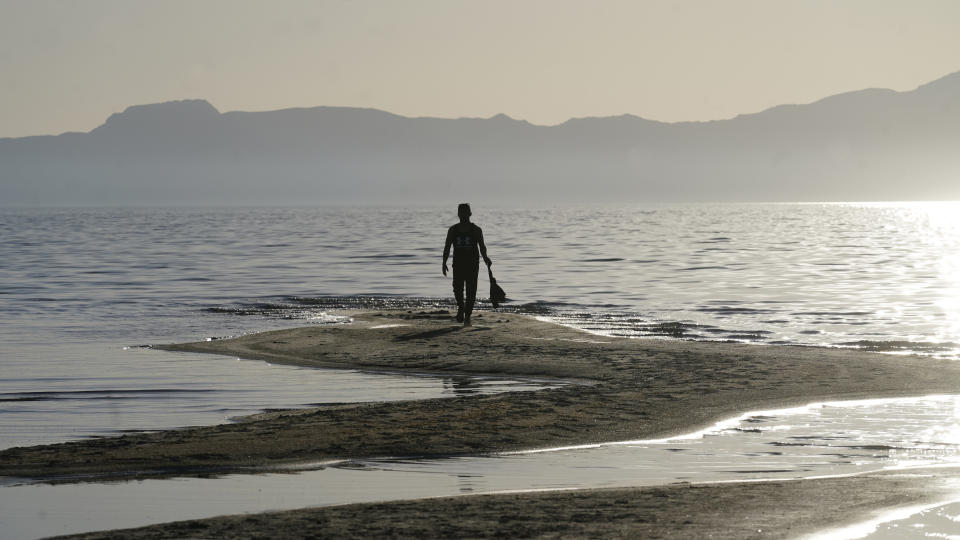 A man walks along a sand bar at the receding edge of the Great Salt Lake on June 13, 2021, near Salt Lake City. The lake has been shrinking for years, and a drought gripping the American West could make this year the worst yet. The receding water is already affecting nesting pelicans that are among millions of birds dependent on the largest natural lake west of the Mississippi River. (AP Photo/Rick Bowmer)
