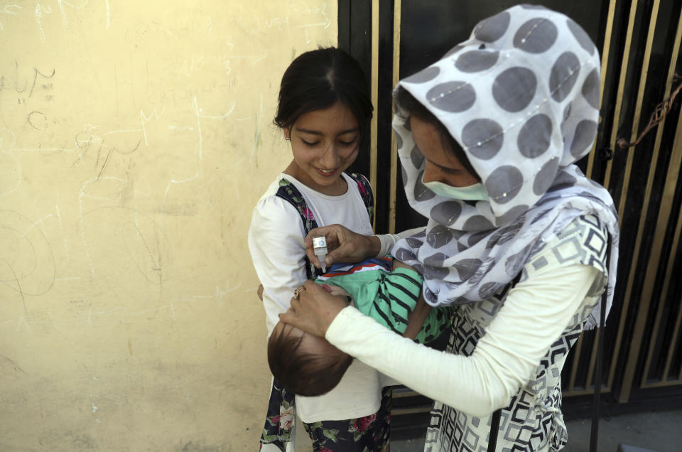 A health worker administers a vaccination to a child during a polio campaign in the old part of Kabul, Afghanistan, Tuesday, June 15, 2021. Gunmen on Tuesday targeted members of polio teams in eastern Afghanistan, killing some staffers, officials said. (AP Photo/Rahmat Gul)