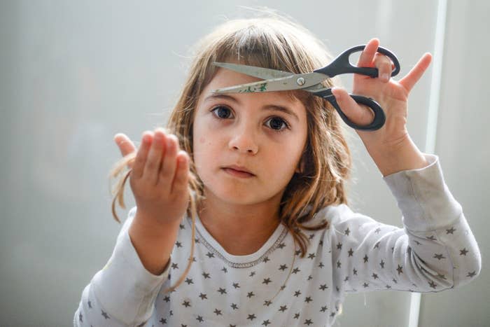 A little girl cutting her hair off with scissors