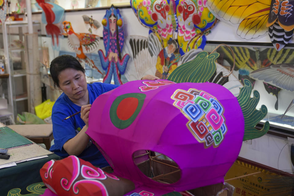 A worker paints a kite at a workshop in Weifang, Shandong Province of China, Friday, April 19, 2024. (AP Photo/Tatan Syuflana)