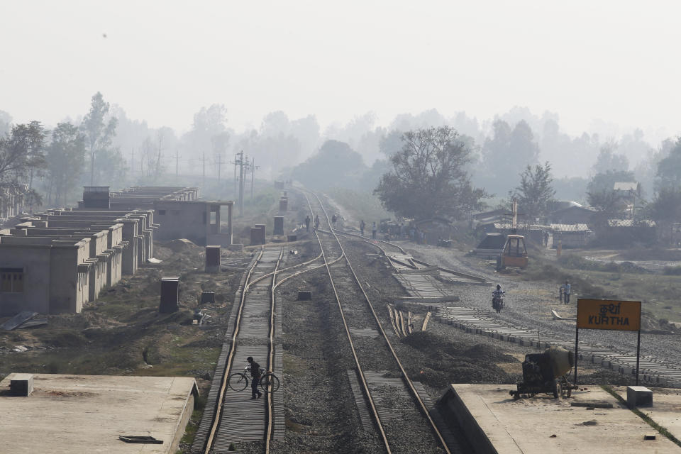 In this Nov. 29, 2018. a Nepalese man carrying his bicycle crosses train tracks at Kurtha near Janakpur, Nepal from where a new rail line connects to Jay Nagar in the Indian state of Bihar. The competition between two Asian giants, India and China, for influence over tiny Nepal is yielding a bonanza in the form of the Himalayan mountain nation’s first modern railway, and possibly more to come. (AP Photo/Niranjan Shrestha)(