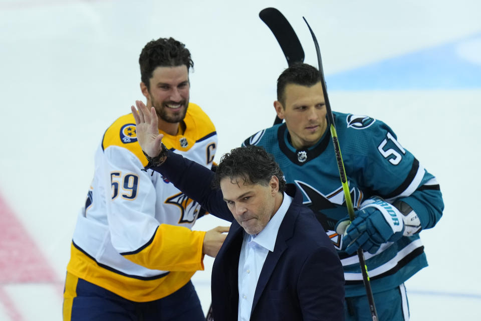 San Jose's Radim Simek, right, and Nashville's Roman Josi, left, watch as NHL legend Czech Republic's Jaromir Jagr greets spectators after an honorable face-off prior the start of the NHL hockey game between San Jose Sharks and Nashville Predators played in Prague, Czech Republic, Saturdday, Oct. 8, 2022. (AP Photo/Petr David Josek)