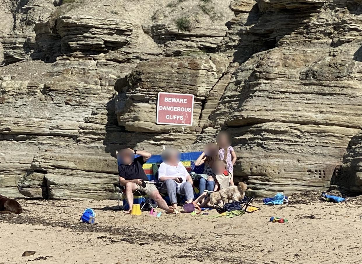 The family were criticised for sunbathing at the foot of a cliff with a sign warning of danger. (Kennedy News)