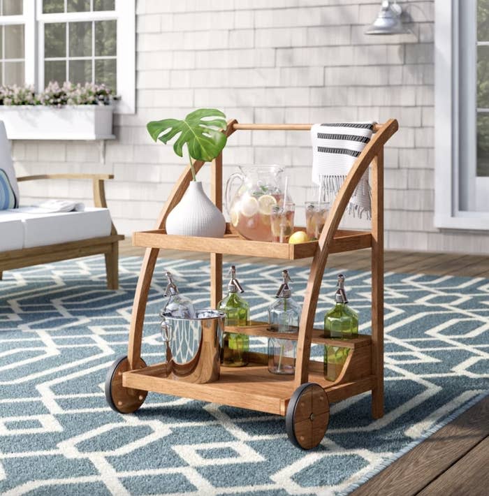 Wooden bar cart with glassware and drinks on a patio