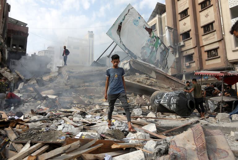 Palestinos inspeccionando daños a edificios y casas en Khan Younis luego de los ataques aéreos israelíes, en el sur de la Franja de Gaza, el 10 de octubre de 2023 (Yousef Masoud/The New York Times)