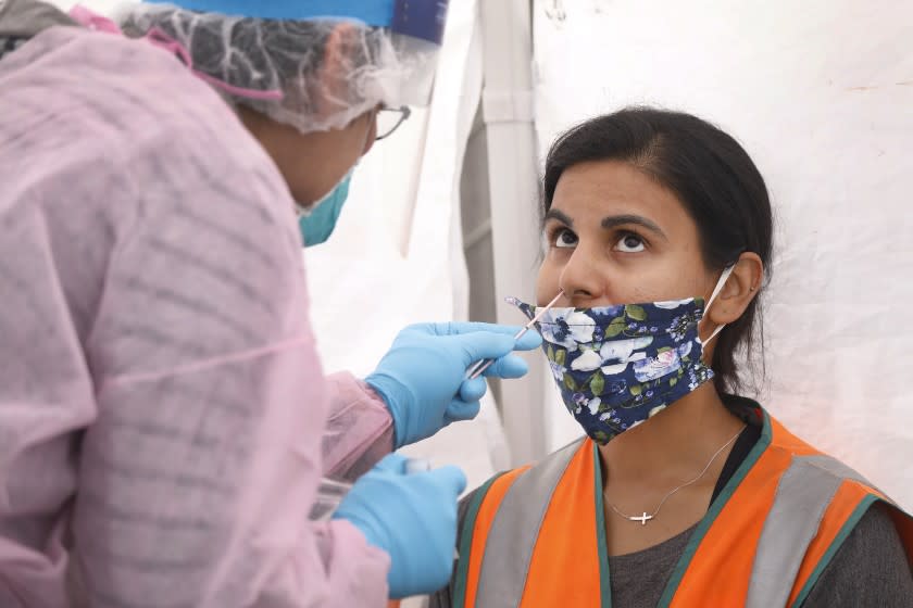 WILMINGTON, CA - JUNE 25: Sabrina Hassan, 34, a safety manager gets a free COVID-19 nasal swab test administered by Nurse Practitioner Alexander Panis, left, as truck drivers and associates working at the ports of Los Angeles and Long Beach take advantage of testing Thursday. The truck drivers union alleges many of the port truck drivers' employers have not been providing proper personal protective equipment and testing priority will be given to drivers to keep workers safe in the era of Coronavirus. Wilmington on Thursday, June 25, 2020 in Wilmington, CA. (Al Seib / Los Angeles Times)