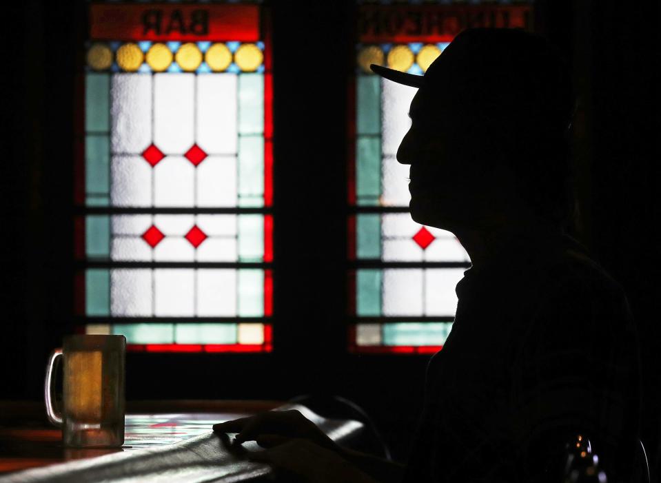 Sunlight passes through the stained glass windows at the front of Larry's Main Entrance as patrons sit at the bar.