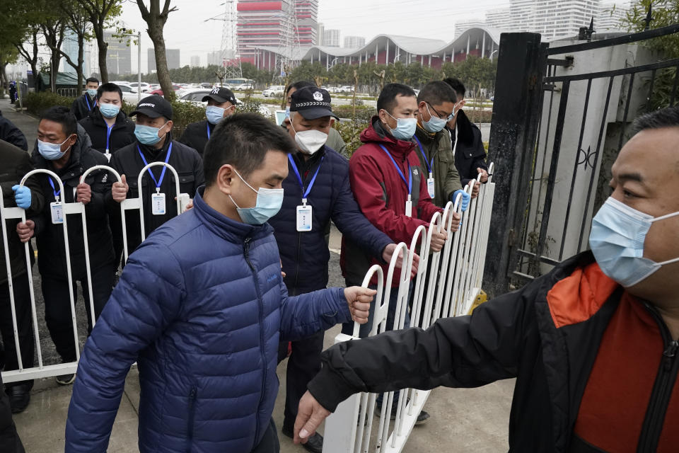 Security personnel move a barrier to clear the way for the World Health Organization team as they depart from the Wuhan Jinyintan Hospital after a field visit in Wuhan in central China's Hubei province on Saturday, Jan. 30, 2021. The World Health Organization team investigating the origins of the coronavirus pandemic visited another Wuhan hospital that had treated early COVID-19 patients on their second full day of work on Saturday. (AP Photo/Ng Han Guan)