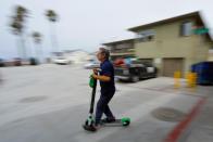 John Heinkel of Scoot Scoop pushes an impounded scooter to a holding garage the company has near the beach, after it was left on private property in San Diego, California