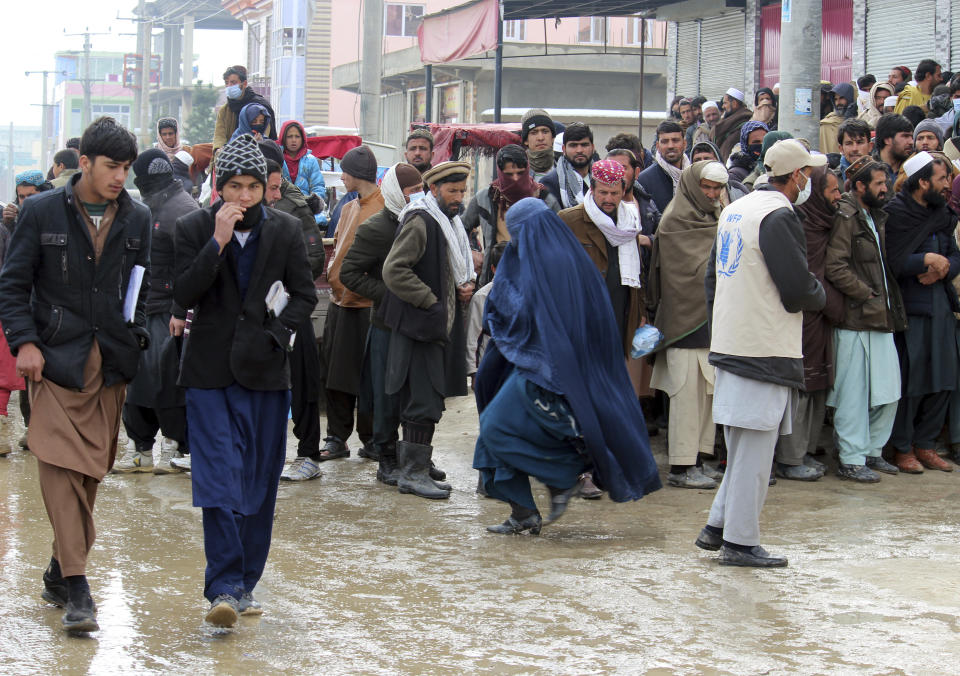 Afghans wait to receive food rations organized by the World Food Program (WFP) in Pul-e-Alam, the capital of Logar province. eastern of Afghanistan, Tuesday, Jan. 18, 2022. The Taliban's sweep to power in Afghanistan in August drove billions of dollars in international assistance out of the country and sent an already dirt-poor poor nation, ravaged by war, drought and floods, spiralling toward a humanitarian catastrophe. (AP Photo/Zubair Abassi)