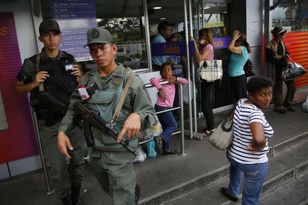 National guards stand at a supermarket entrance as people line up outside in Caracas January 19, 2015. REUTERS/Jorge Silva