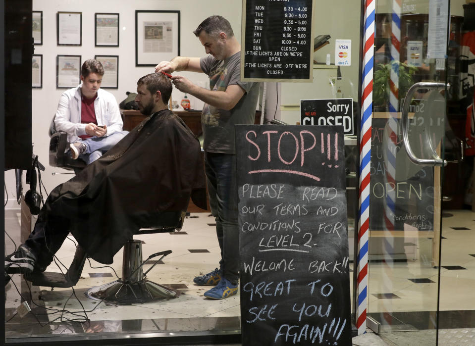 Cathedral Junction Barbers owner Conrad Fitz-Gerald cuts the hair of a customer just past midnight in Christchurch, New Zealand, Thursday, May 14, 2020. New Zealand lifted most of its remaining lockdown restrictions from midnight Wednesday (noon Weds. GMT) as the country prepares for a new normal. Malls, retail stores and restaurants will reopen and many people will return to their workplaces. (AP Photo/Mark Baker)