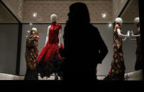 A museum assistant poses with dresses at the Alexander McQueen: Savage Beauty exhibition at the V&A in London, March 12, 2015. REUTERS/Suzanne Plunkett