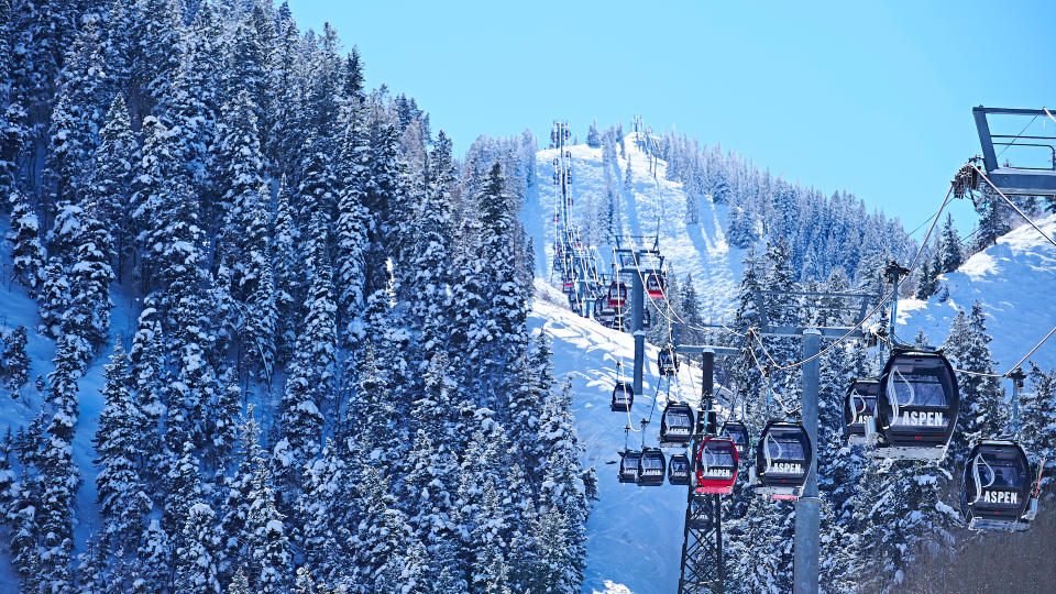 Cable car moving up over forested snow covered mountains, Aspen, Colorado, USA