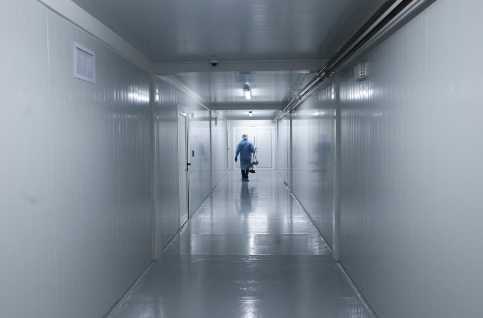 A worker wearing protective gear walks down the corridor of a new health facility, built on a parking lot of the Albrook shopping mall, that will take in patients infected with the new coronavirus, during a media presentation in Panama City, Thursday, April 16, 2020. (AP Photo/Arnulfo Franco)