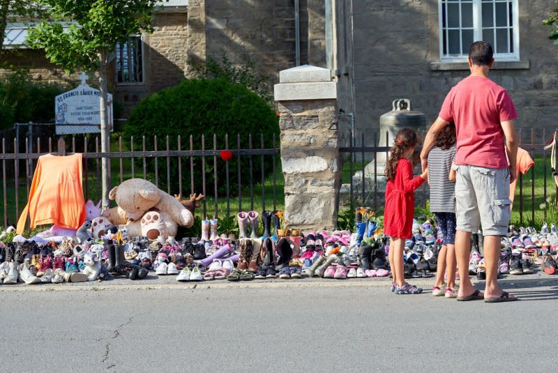 A father and his children walk near a tribute in front of the Catholic St-Franics Xavier Mission for the 215 children buried in an unmarked mass grave on the grounds of the former Kamloops Indian Residential School in Kahnawake reserve, Canada, in 2021. File Photo by Andre Pichette/EPA-EFE