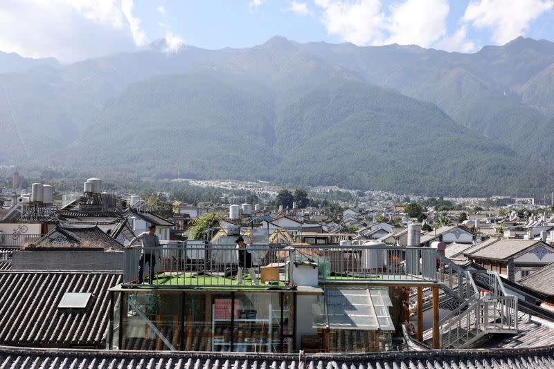 People set up a carpet on a rooftop overlooking the old town of Dali