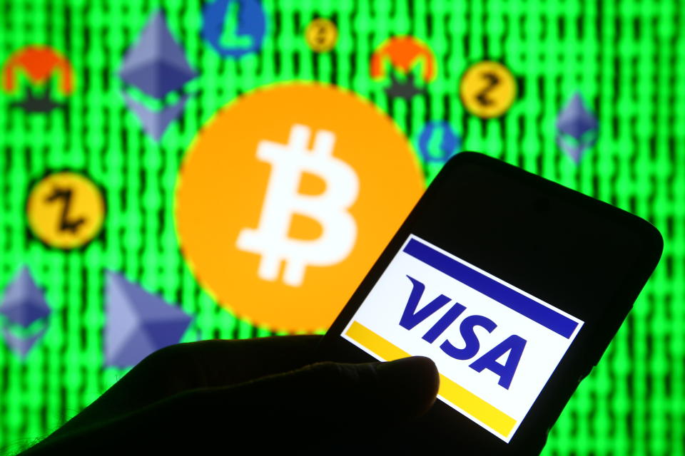 UKRAINE - 2021/02/12: In this photo illustration a Visa logo is seen on a mobile phone in front of Bitcoin and other cryptocurrencies signs. (Photo Illustration by Pavlo Gonchar/SOPA Images/LightRocket via Getty Images)