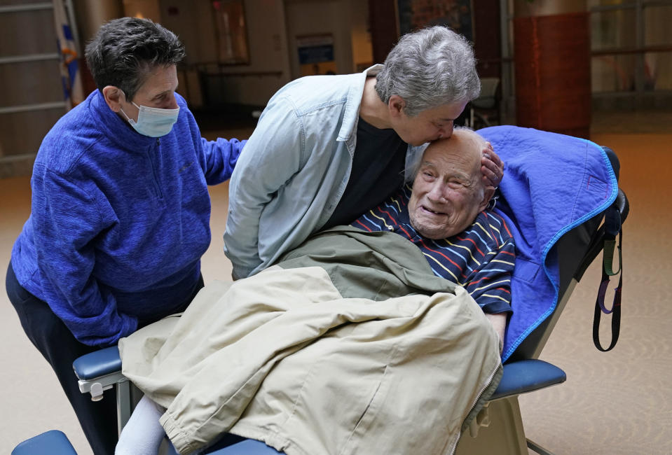 FILE - Melvin Goldstein, 90, smiles as his daughter Barbara Goldstein gives him a kiss on the head during their first in-person, indoor family visit inside the Hebrew Home at Riverdale, Sunday, March 28, 2021, in the Bronx borough of New York. A focus on the elderly at the start of the nation's vaccination campaign helped protect nursing homes that were ravaged at the height of the U.S. coronavirus outbreak, but they are far from in the clear. New outbreaks, often traced to infected staff members, are still occurring in long-term care centers across the country, causing continued havoc for visitation policies. (AP Photo/Kathy Willens)