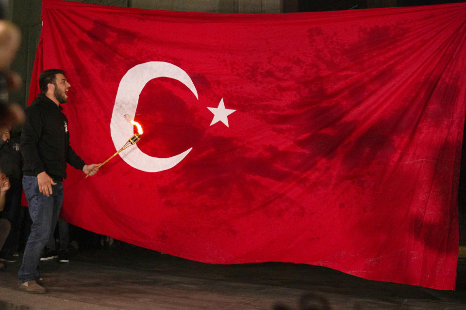 A man prepares to set a Turkish national flag on fire during a demonstration marking the 106th anniversary of the massacre and honors the victims of Armenian Genocide, Saturday, April 24, 2021, in Yerevan, Armenia. Armenians marked the anniversary of the death of up to 1.5 million Armenians by Ottoman Turks, an event widely viewed by scholars as genocide, though Turkey refutes the claim. (Grigor Yepremyan/PAN Photo via AP)