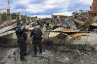 Australian Federal Police inspect burnt out areas of Chinatown in Honiara, Solomon Islands, Tuesday, Nov. 30, 2021. New Zealand announced Wednesday, Dec. 1, 2021, that they will send up to 65 military and police personnel to the Solomon Islands over the coming days after rioting and looting broke out there last week.(Gary Ramage via AP)