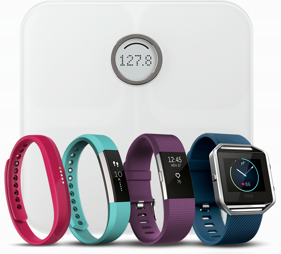 Five of Fitbits devices, a smart scale and four wristband worn activity trackers.