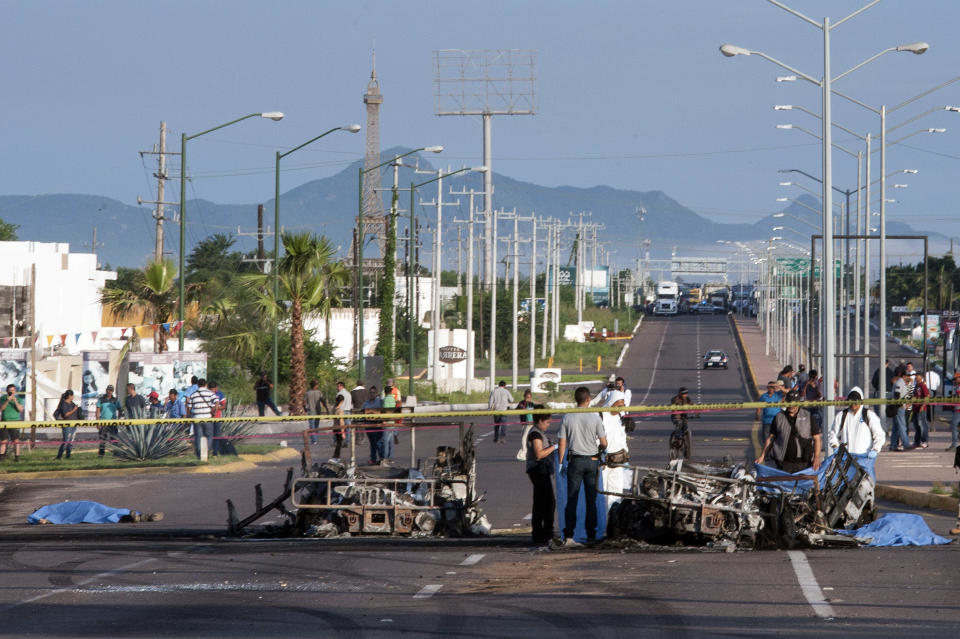 FILE - In this Sept. 30, 2016 file photo, police investigators examine the site where a military convoy was ambushed with grenades and high-powered guns, killing five soldiers in the city of Culiacan, Mexico. Local military commander Gen. Alfonso Duarte said it is very probable that the attack was carried out by the sons of imprisoned drug lord Joaquin "El Chapo" Guzman. (AP Photo/Hector Parra, File)