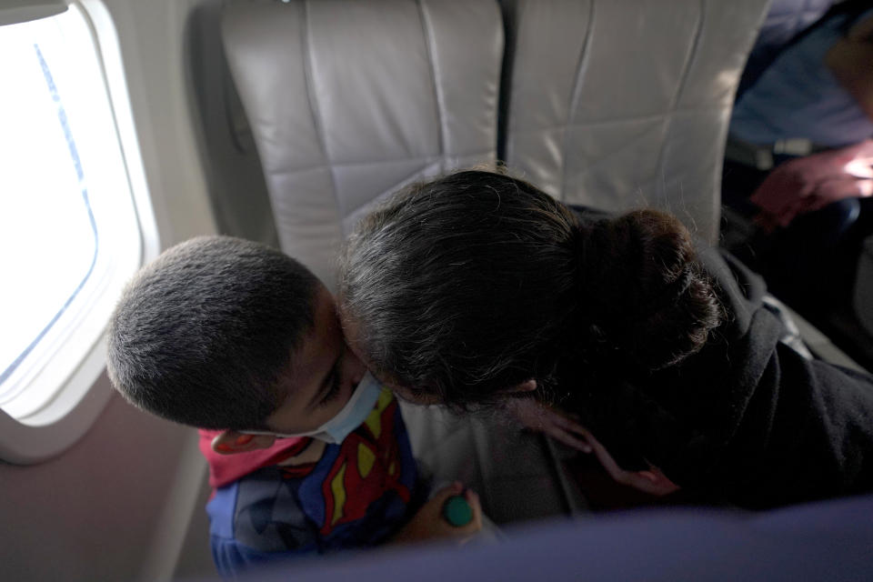 Celestina Ramirez, right, a migrant from Honduras, kisses her son Yancarlos Amaya, 5, while riding on an airplane to Houston, Wednesday, March 24, 2021, in Harlingen, Texas. The mother and son, who are headed to Baltimore to reunite with Ramirez's brother, were granted to stay in the U.S. after turning themselves to U.S. (AP Photo/Julio Cortez)