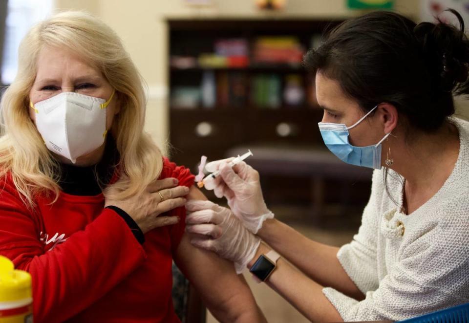 Sherry Barclay, a licensed practical nurse, gets a Moderna COVID-19 vaccine from Dr. Jennifer Henzler of CVS Pharmacy, at Wellmore of Lexington on Wednesday, Dec. 30, 2020. Barclay said she was excited to get the extra layer of virus protection after she was diagnosed with COVID-19 in October but showed no symptoms.