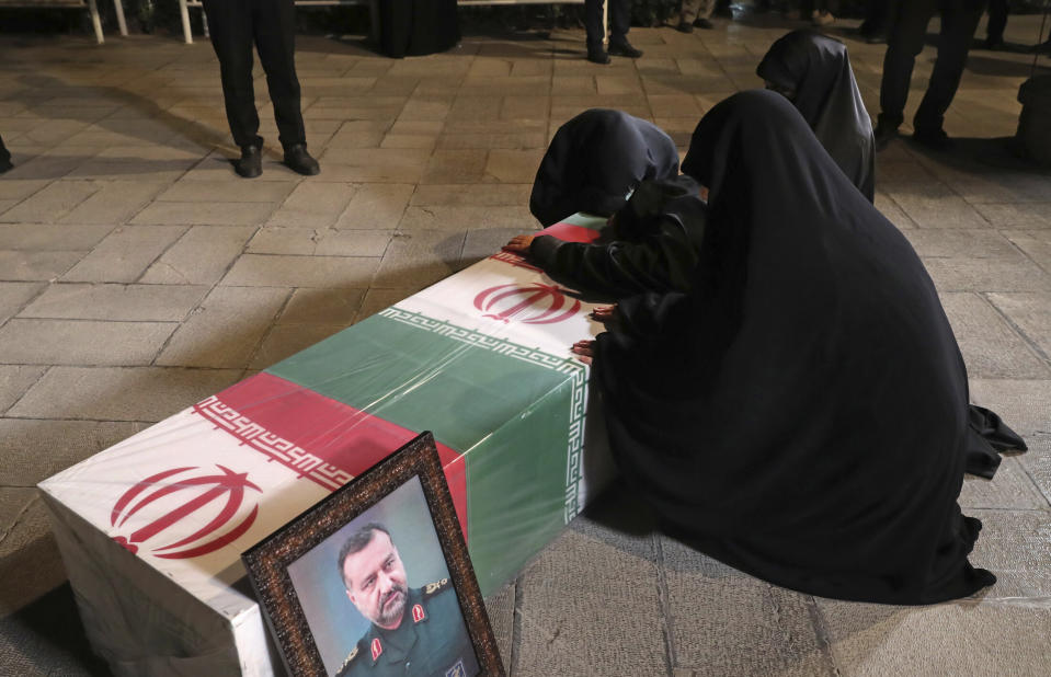 In this photo released by the official website of the office of the Iranian supreme leader, family members of Seyed Razi Mousavi, a high ranking Iranian general of the paramilitary Revolutionary Guard, who was killed in an alleged Israeli airstrike in Syria on Monday, mourn over his flag-draped coffin at supreme leader's office compound in Tehran, Iran, Thursday, Dec. 28, 2023. (Office of the Iranian Supreme Leader via AP)