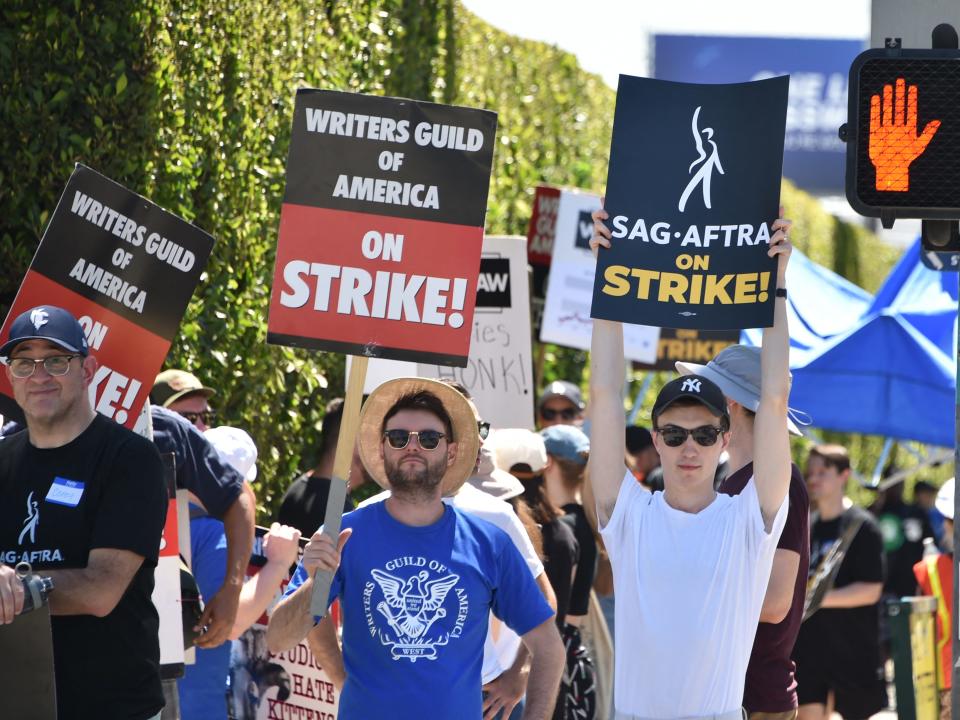 image of striking actors holding up picket signs in Hollywood