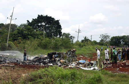 Rescue team members work in the wreckage of a Boeing 737 plane that crashed in the agricultural area of Boyeros, around 20 km (12 miles) south of Havana, shortly after taking off from Havana's main airport in Cuba, May 18, 2018. REUTERS/Alexandre Meneghini