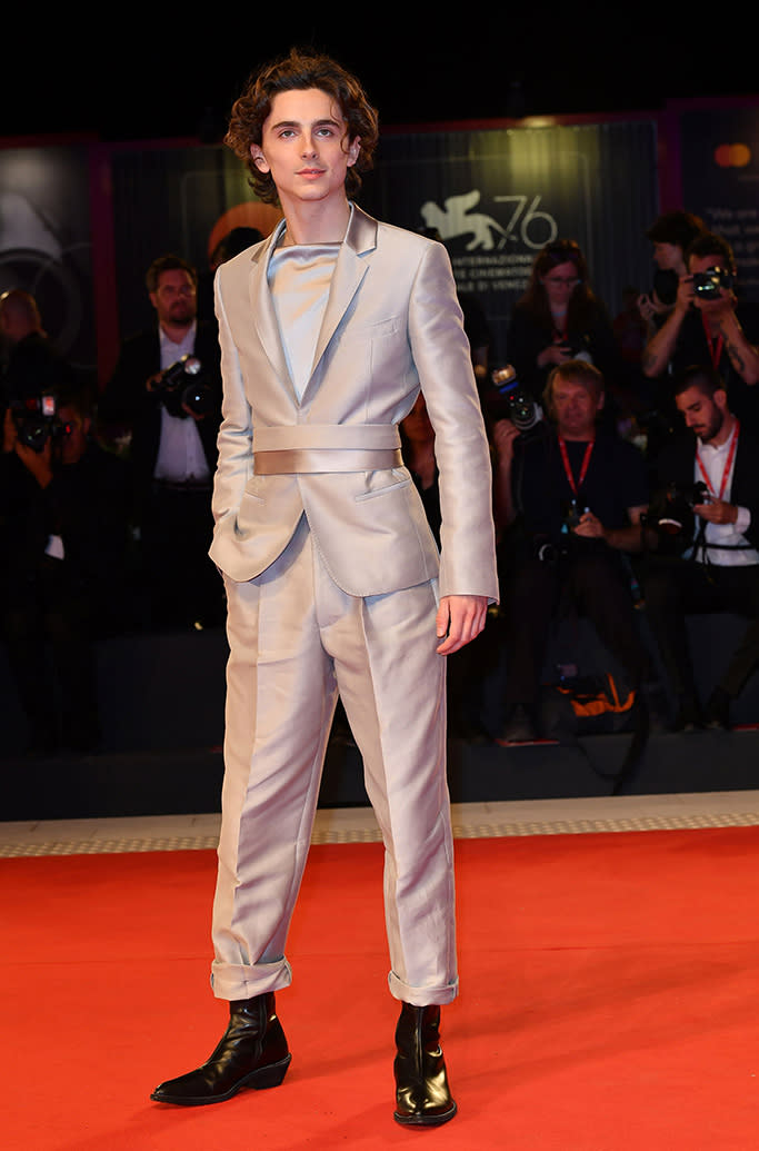 Timothée Chalamet at the Venice Film Festival in another Haider Ackermann look, which consisted of futuristic fine lines and a sleek silver sheen. This time, he paired the suit with Western-inspired boots. - Credit: Maria Laura Antonelli/Shutterstock