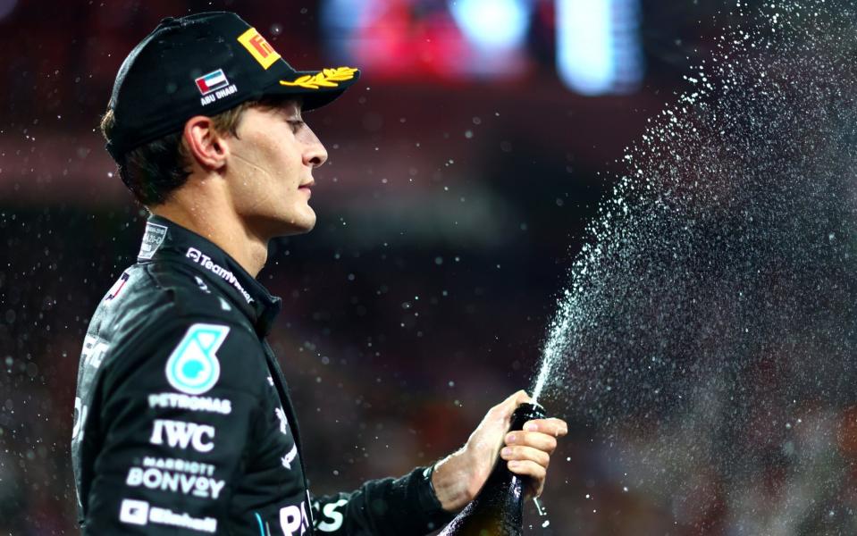 A sullen-looking George Russell sprays champagne on the podium in Abu Dhabi