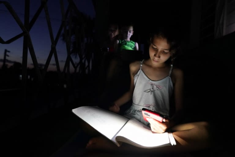 Una joven de Guanajay (al oeste de La Habana) usa la linterna de su teléfono móvil para estudiar.