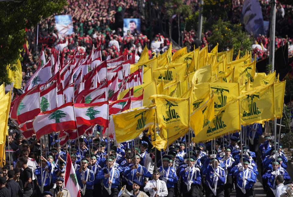 Lebanese Shiite scouts of the Iranian-backed Hezbollah group carry their group and Lebanese flags as they march during the holy day of Ashoura that commemorates the 7th century martyrdom of the Prophet Muhammad's grandson Hussein, in the southern suburb of Beirut, Lebanon, Tuesday, Aug. 9, 2022. The leader of Lebanon's Hezbollah group Sheikh Hassan Nasrallah warned archenemy Israel on Tuesday over the two countries' maritime border dispute. (AP Photo/Hussein Malla)