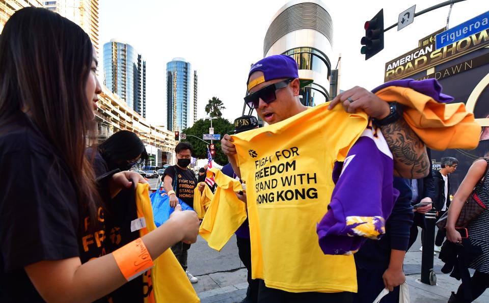 Hong Kong supporters hand out free t-shirts outside Staples Center ahead of the Lakers vs Clippers NBA season opener in Los Angeles on October 22, 2019. - Activists handed out free T-shirts displaying support for the Hong Kong protests after an NBA fan in Northern California raised enough money to pay for more than 10,000 shirts, according to the organizer who goes by the pseudonym "Sun Lared" as LeBron James of the Lakers suffers the brunt of people's anger after comments he made in response to the tweet from Houston Rockets GM Daryl Morey in support of Hong Kong protesters, and drawing the ire of the Chinese Communist Pary. (Photo by Frederic J. BROWN / AFP) (Photo by FREDERIC J. BROWN/AFP via Getty Images)