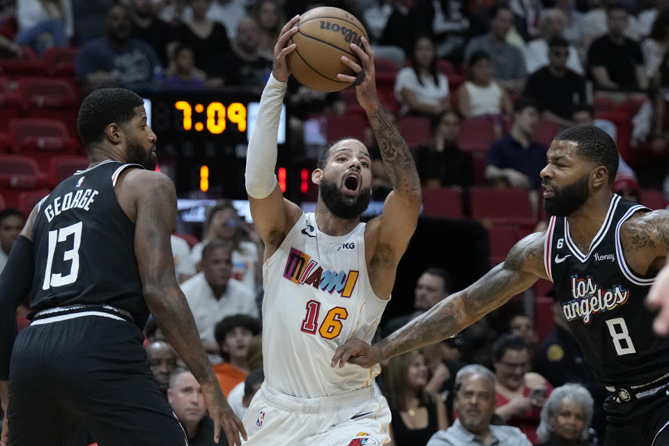 Miami Heat forward Caleb Martin (16) attempts to pass past Los Angeles Clippers forwards Paul George (13) and Marcus Morris Sr. (8) during the first half of an NBA basketball game, Thursday, Dec. 8, 2022, in Miami. (AP Photo/Wilfredo Lee)