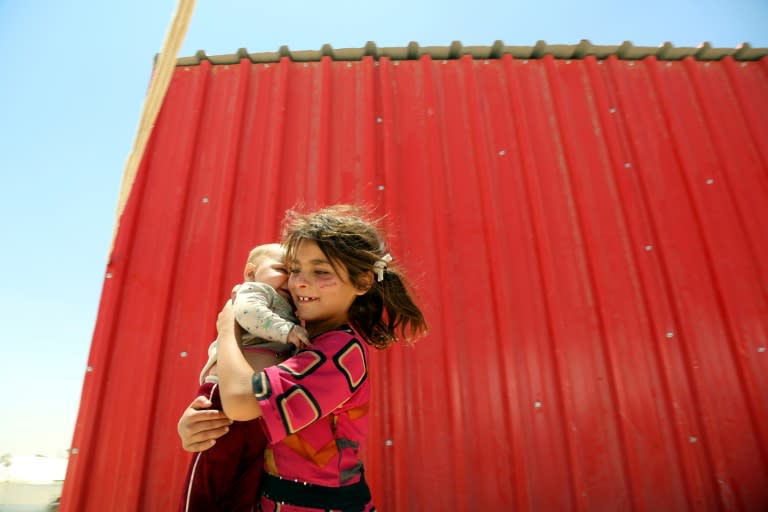 A displaced Syrian girl carries a baby on June 10, 2017 at a temporary camp in the northern Syrian village of Ain Issa, where many people who fled the Islamic State group stronghold of Raqa are taking shelter