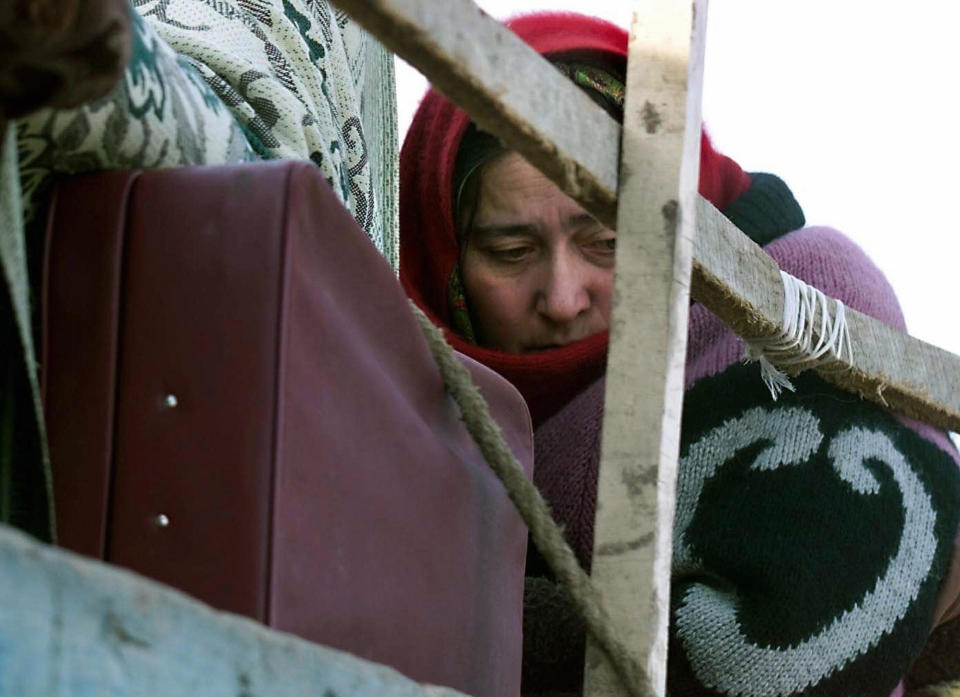 A Chechen refugee, with an anguished expression, is seen sitting on a truck.