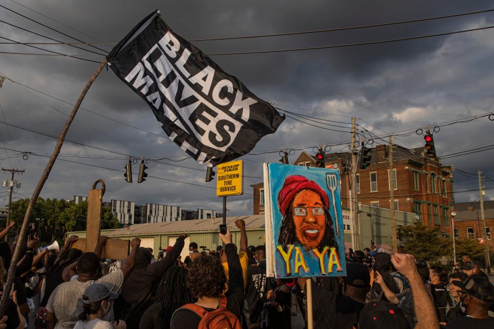 Flags and signs wave through the air at sunset as protesters march through into the Nulu neighborhood on Friday evening. Sept. 25, 2020