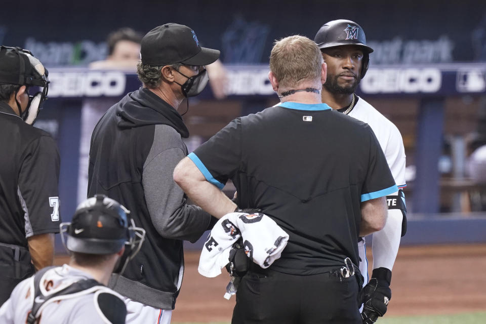 Miami Marlins manager Don Mattingly, center, and a trainer talk to batter Starling Marte before escorting him back to the dugout during the ninth inning of a baseball game against the San Francisco Giants, Sunday, April 18, 2021, in Miami. The Giants defeated the Marlins 1-0.(AP Photo/Marta Lavandier)