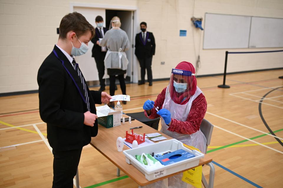 <p>Year 10 students hand over completed lateral flow Covid-19 tests to staff in the Sports Hall at Park Lane Academy in Halifax, northwest England on March 17, 2021. (Photo by Oli SCARFF / AFP) (Photo by OLI SCARFF/AFP via Getty Images)</p>
