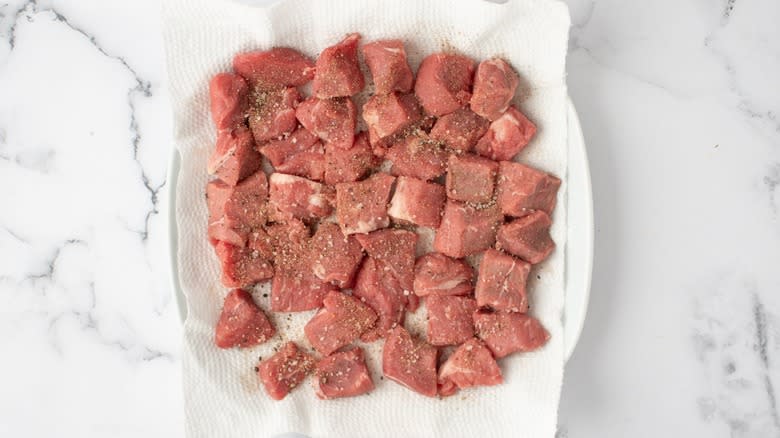 seasoned raw beef chunks on paper towel