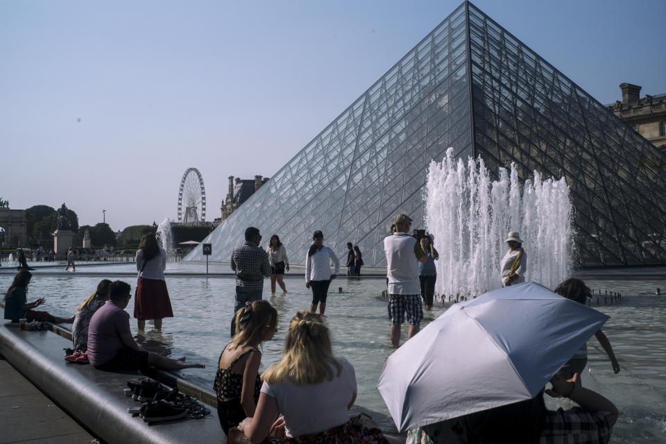 People cool off next to the fountains at Louvre Museum in Paris, France, Wednesday, July 24, 2019. Temperatures in Paris are forecast to reach 41 degrees C (86 F), on Thursday. (AP Photo/Rafael Yaghobzadeh)