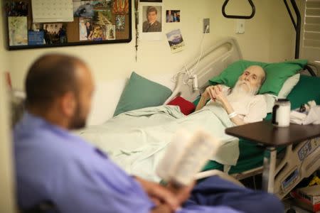 Pastoral Care Services Worker and inmate Billy Ray Worth (L) reads Harry Potter to inmate Michael Patrick Rodriguez, 62, who has skin cancer, in the hospice at the California Medical Facility prison in Vacaville, California, U.S., May 23, 2018. "I'm going to beat this thing - get out. I'm going to beat this cancer," Rodriguez said. "They're helpful (the pastoral care service inmates). They're doing everything we want that we couldn't do before... One guy that comes in here is reading a Harry Potter book for me." REUTERS/Lucy Nicholson