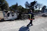 <p>A fireman walks past charred debris of vehicles that were destroyed by fire in a parking lot for camping cars in Bormes-les-Mimosas, in the Var department, France, July 26, 2017, after firefighters evacuated thousands of campers and local residents when a wildfire broke out on France’s tourist-thronged Riviera coast overnight. (Jean-Paul Pelissier/Reuters) </p>